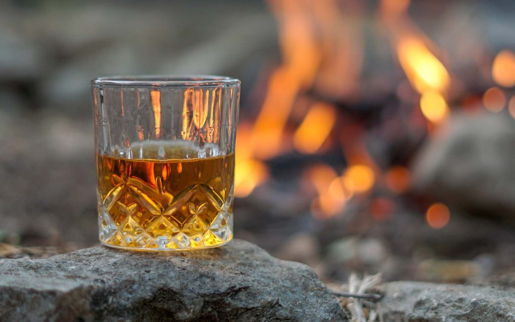 verre de whisky devant un feu de bois